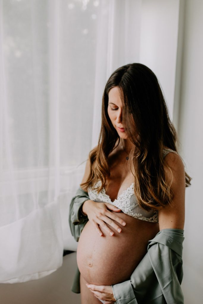 Mum to be photoshoot. Hampshire photographer. mum to be is wearing a lovely underwear and looking down on her baby. London photographer. Ewa Jones Photography
