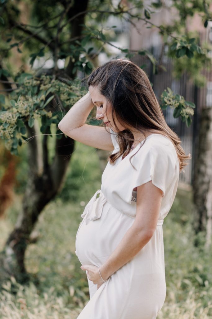 Expecting mum is looking down at the bump. Natural outdoor photo session. Ewa jones photography