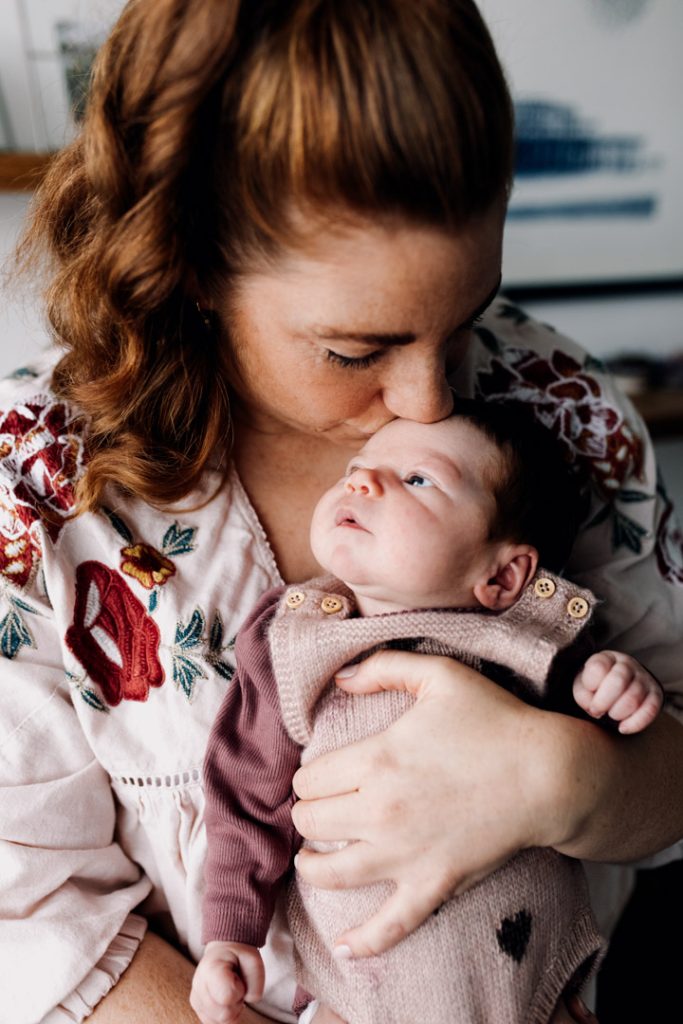 Mum is kissing newborn girl and holding tight. Newborn photographer in Hampshire. Basingstoke photographer. Ewa Jones Photography