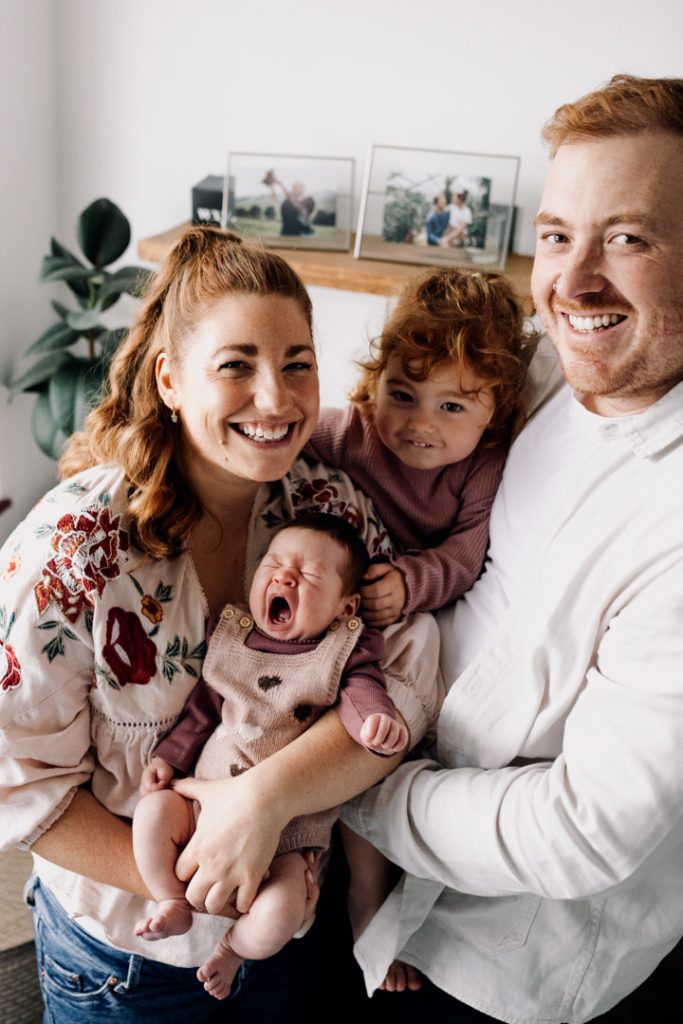 family of four is cuddling close and smiling. Newborn photo session with a toddler. Basingstoke newborn photographer. Ewa Jones Photography