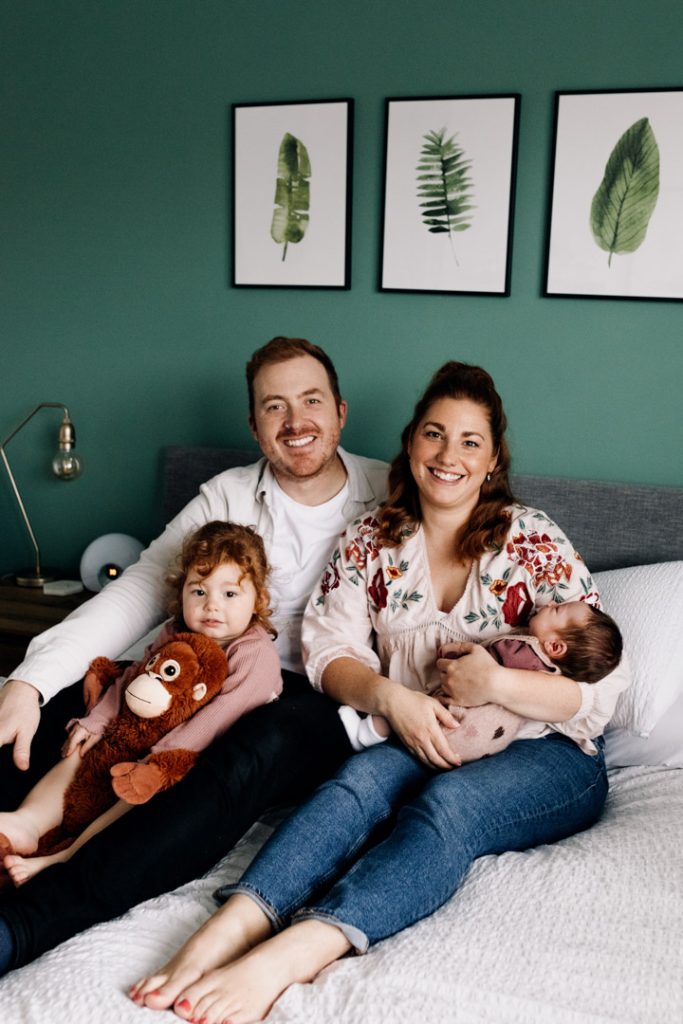 Family is sitting on the bed and cuddling.in home newborn photo shoot in Hampshire. Ewa Jones Photography