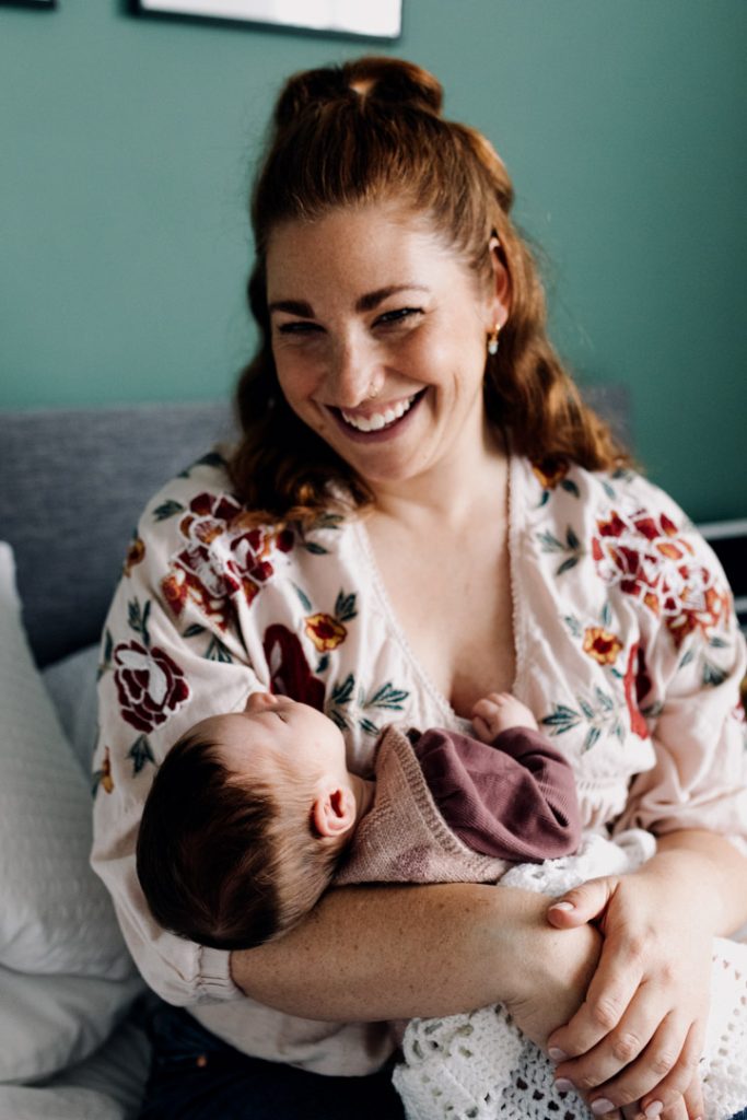 Mum is holding newborn baby girl and smiling. Newborn photo session at home. Hampshire photographer. Ewa Jones Photography