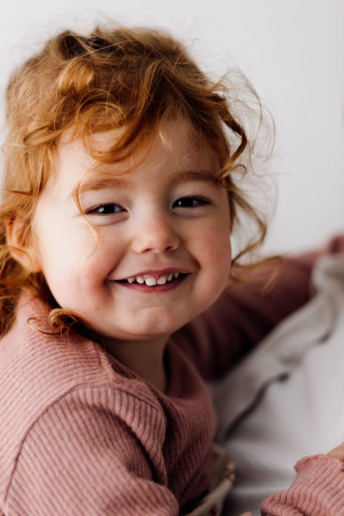 Little girl is smiling at the camera. Newborn in-home photo session with a toddler. Hampshire photographer. Basingstoke photographer. Ewa Jones Photography