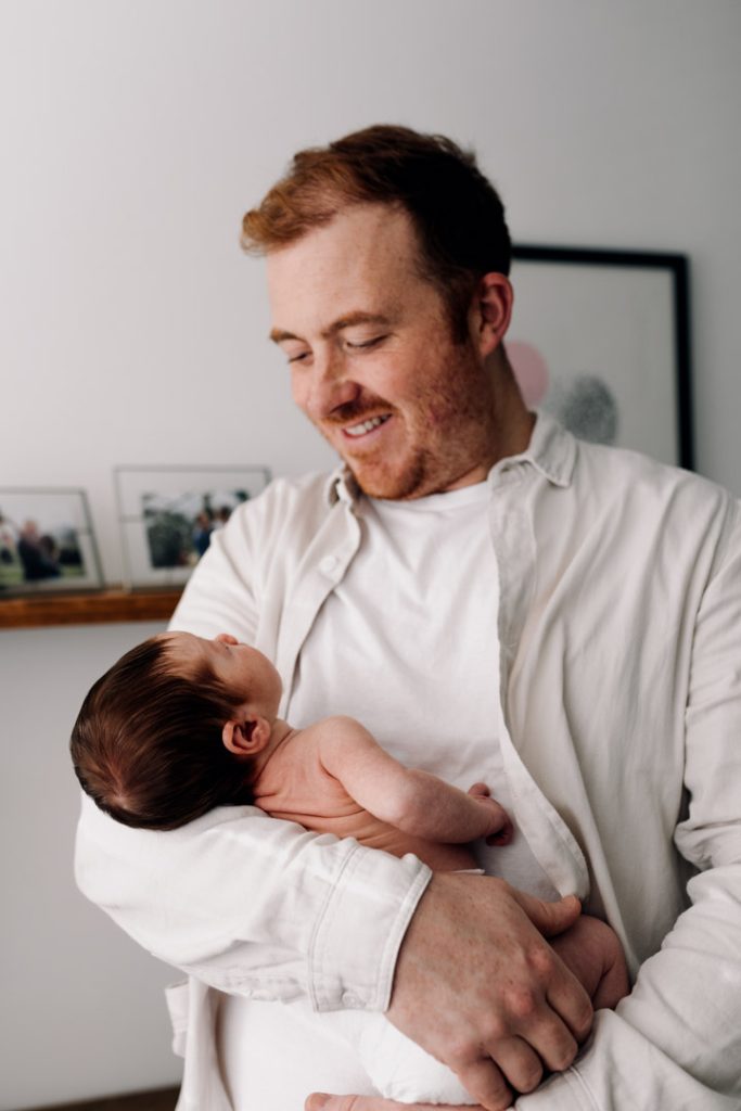 Dad is holding his newborn baby in his arms. Newborn photo session in Hampshire. Hampshire photographer. Ewa Jones Photography
