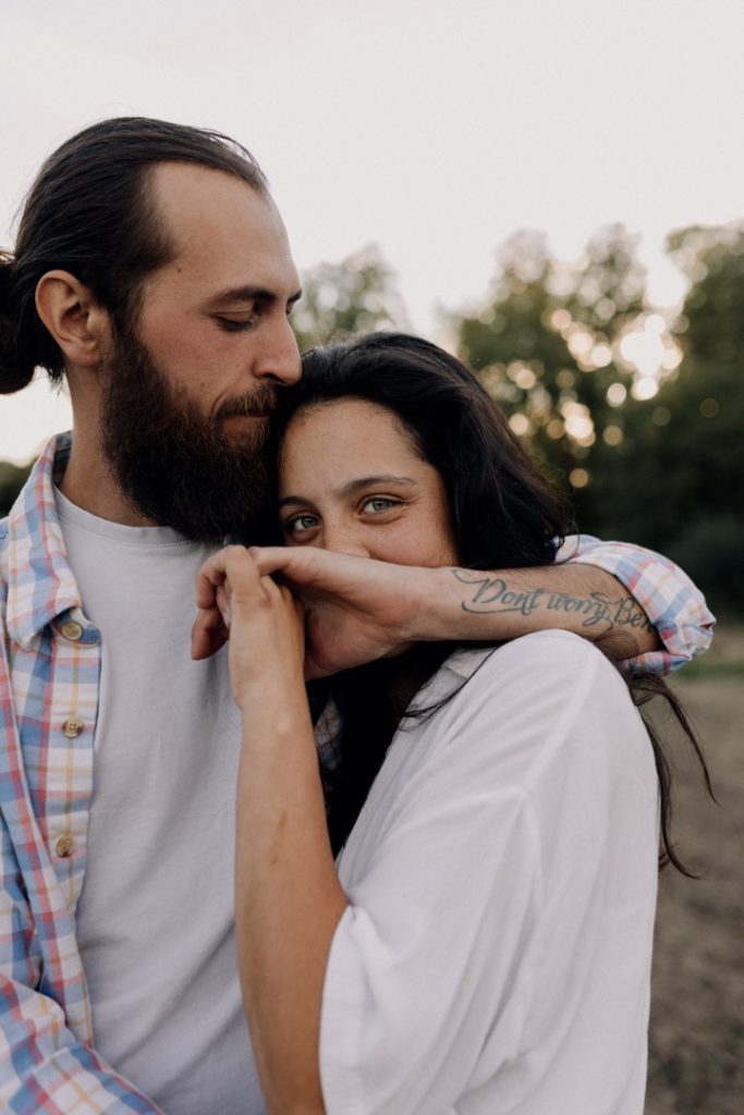 Close up of a couple cuddling. female is looking at the camera and secretly smiling. Hampshire photographer. Ewa Jones Photography