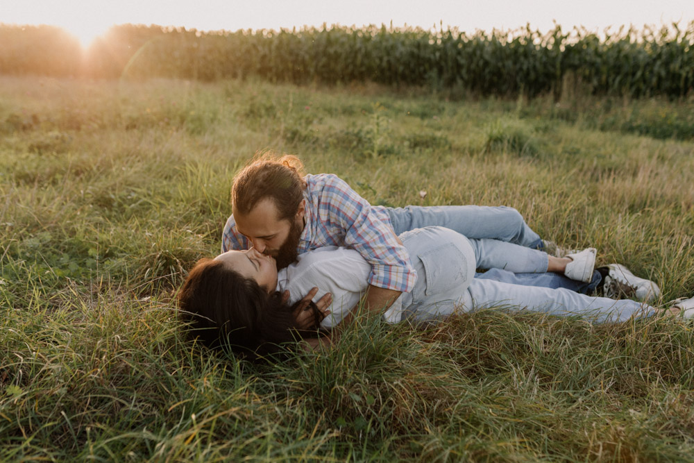 Couple is laying on the grass and kissing. Intimate and relaxed couple's photo shoot in the Hampshire country side. Hampshire photo shoot. Basingstoke photographer. Ewa Jones Photography