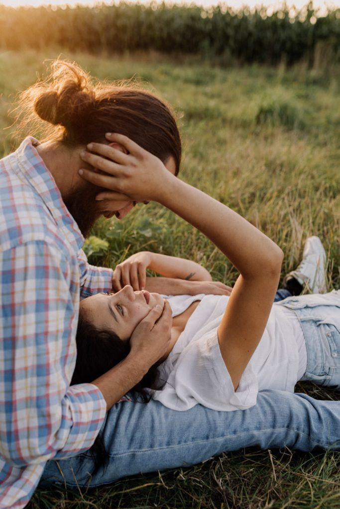 Female is laying on the grass and looking up at her partner. Lovely couples photo session during golden hour. Hampshire photo session. Ewa Jones Photography