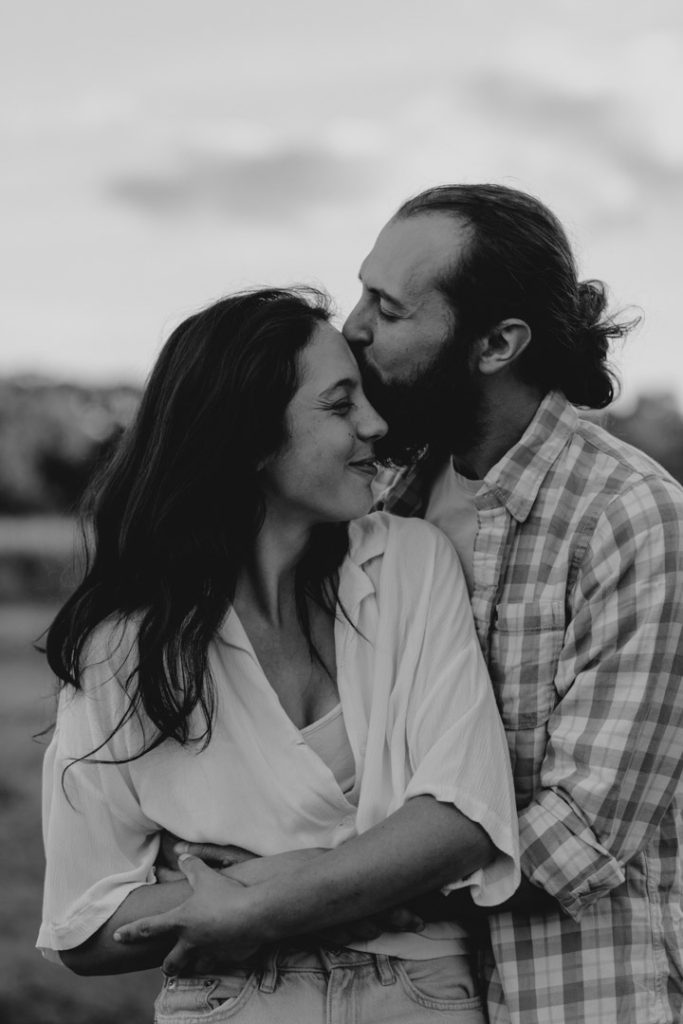 Couple is holding close each other and being connected with each other. the man is kissing his partner on her forehead. lovely natural couple photo shoot in Hampshire. Ewa Jones Photography