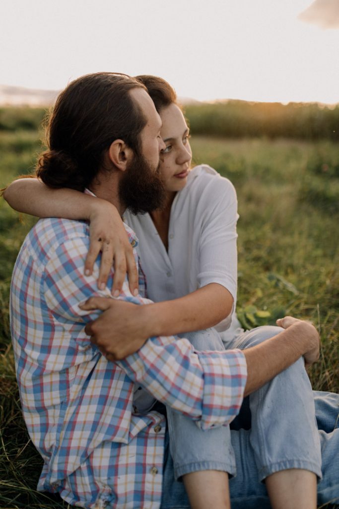 Female is sitting on male lap and looking away. Lovely intimate and peaceful photograph. Couple enjoying their love. Hampshire photo shoot in Hampshire. Ewa Jones Photography