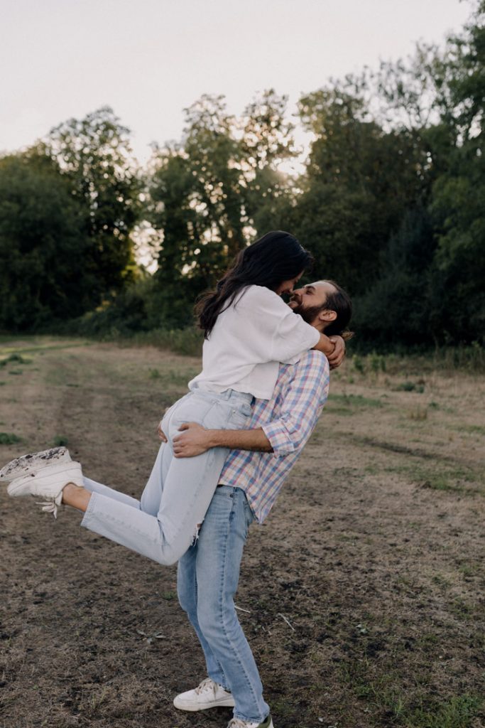 A man is lifting his partner up and they are smiling to each other. Hampshire couple photographer. Ewa Jones Photography