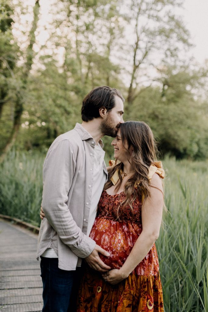 parents to be are standing and cuddling with each other. they both have hands placed on the bump. maternity photo shoot. Ewa Jones Photographer