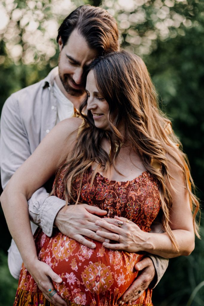 intimate moment of parents cuddling close and holding baby bump. natural lifestyle bump to baby photo session. Hampshire family photographer. Ewa Jones Photographer