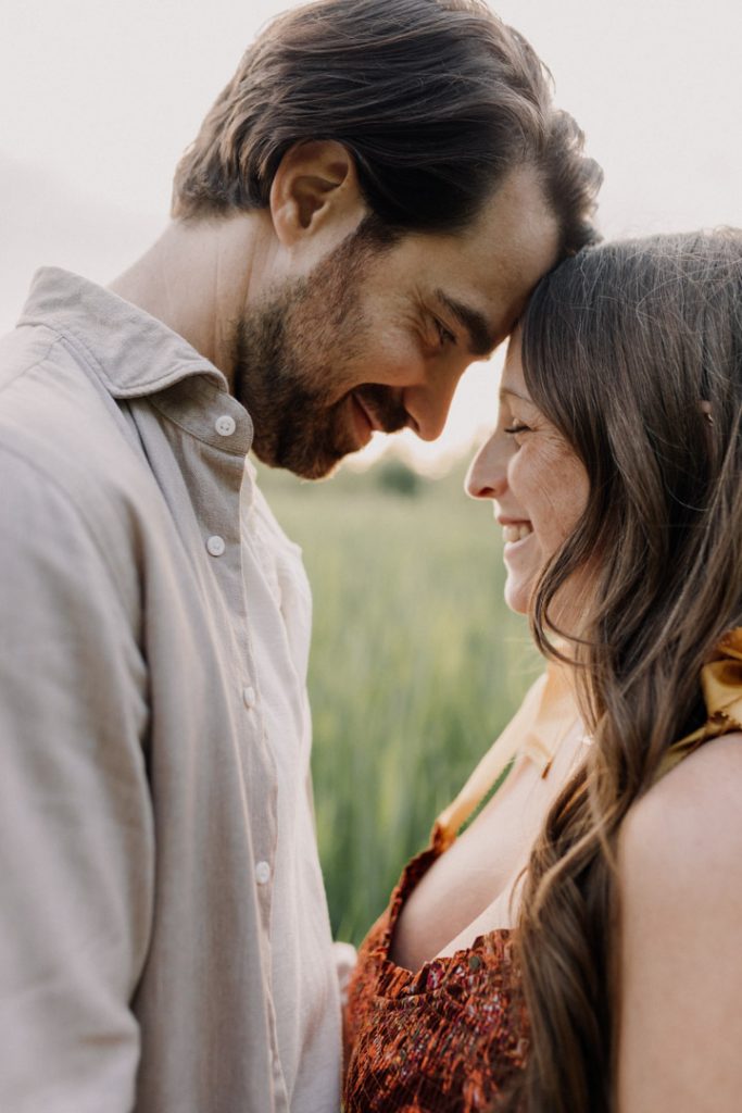 Mum and dad are touching foreheads and smiling. golden hour is peaking through. Bump photo session. Hampshire photographer. Ewa Jones Photographer