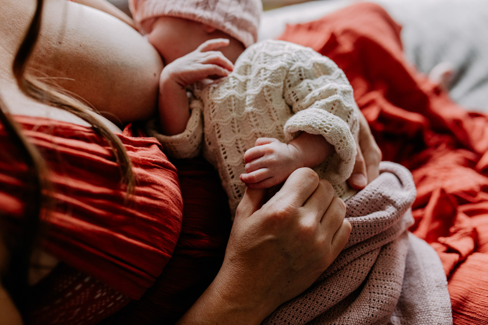 Mum is holding her baby. baby is breastfeeding. intimate and relaxing photo session at home. Hampshire photo shoot. Hampshire photographer. Ewa Jones Photography