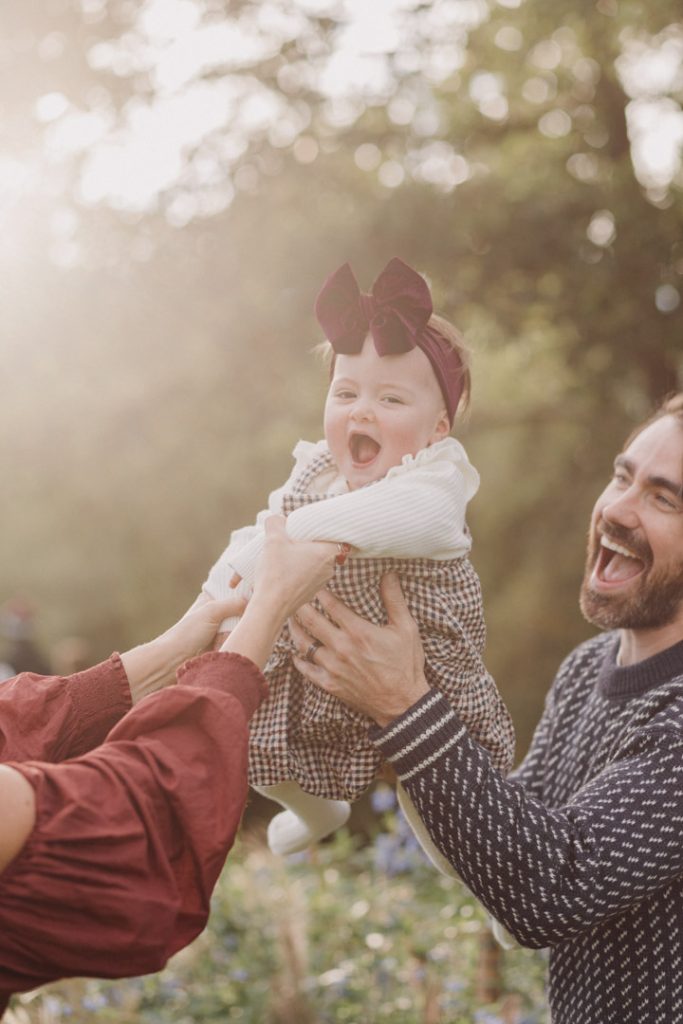 Dad is lifting his one year old daughter and she is enjoying being lifted in the air. family photo shoot for one year old birthday. Hampshire photo shoot. Hampshire photographer. Ewa Jones Photography