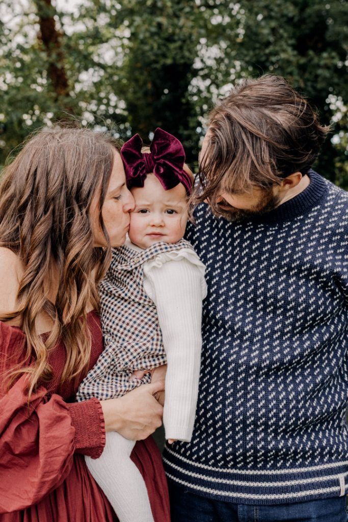 Mum is kissing her daughter on her cheek. stylish family photo shoot. what to wear for family photo session. celebrating one year old with a natural photo shoot. Ewa Jones Photographer