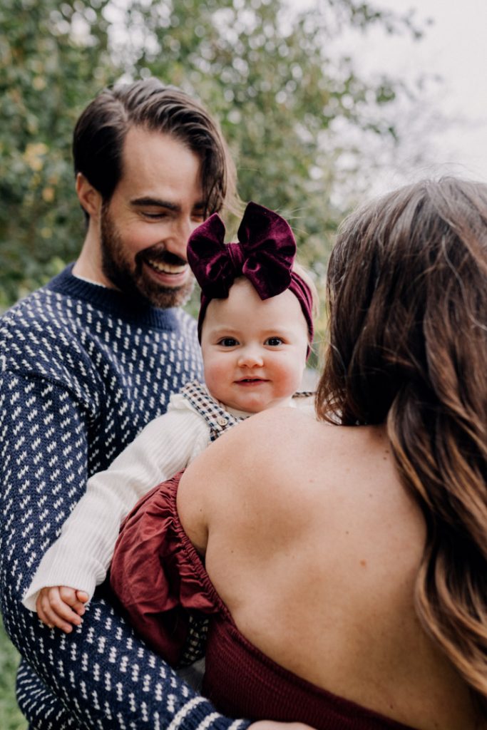 mum is holding her one year old girl and the girl is looking and smiling at the camera. Lovely natural lifestyle photo shoot in Hampshire. Family photo shoot in Hampshire. Ewa Jones Photography