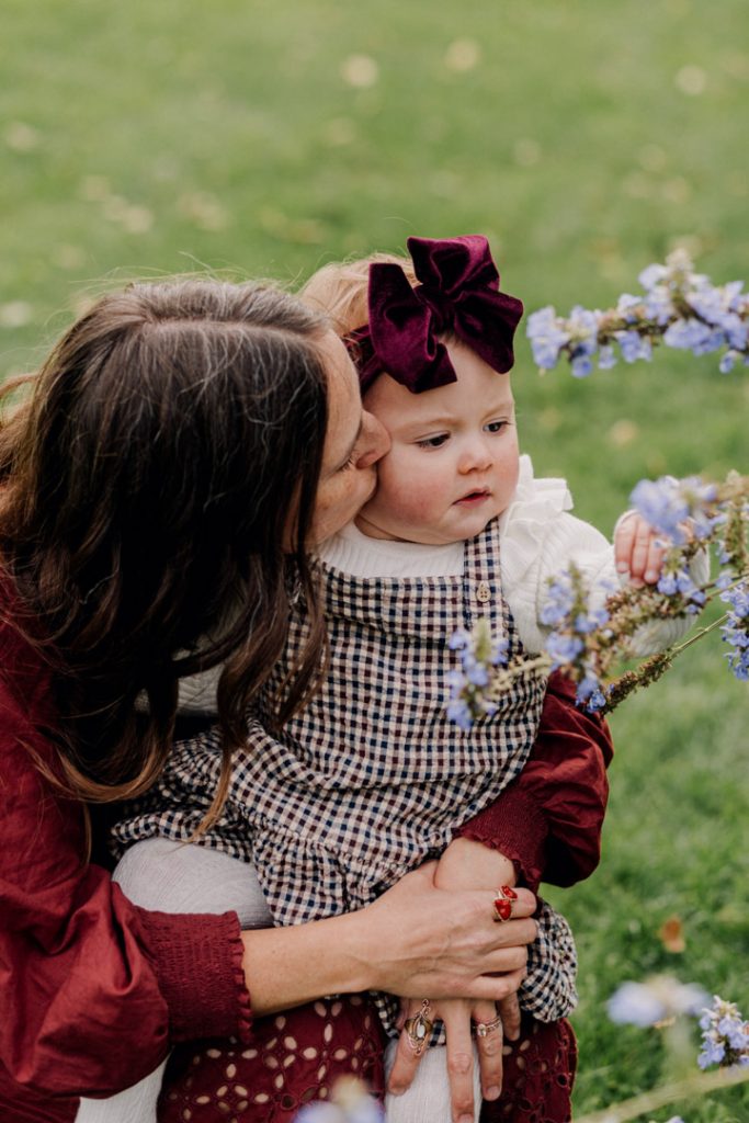 One year old girl is looking at the flowers and is very interested. Capturing lovely moments during natural lifestyle family photo session. Mum and daughter. Hampshire photo shoot. Ewa Jones Photography