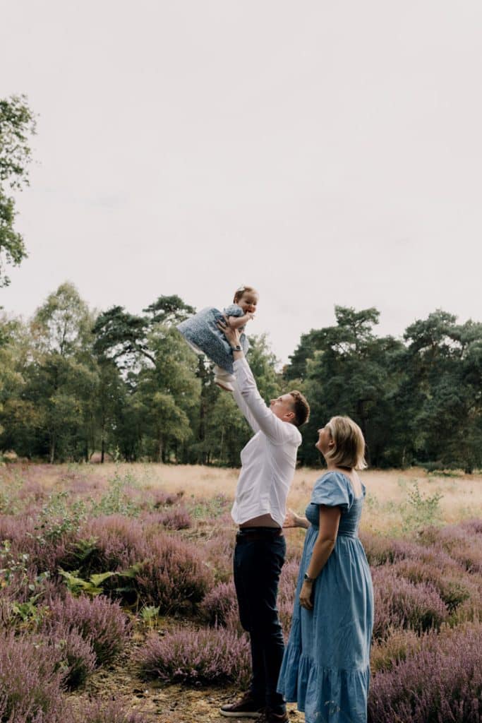Dad is throwing his little girl in the air. She is looking at the camera and smiling. Lovely natural family moments captures on camera. Berkshire family photo shoot. Hampshire family photo shoot. Ewa Jones photography