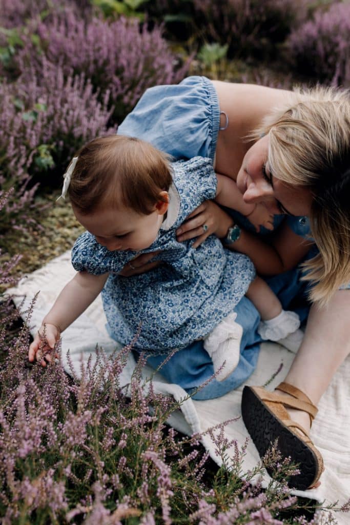 Mum is holding baby girl and looking down on her. family photo session outside in the Berkshire nature common. Hampshire photo shoot. Ewa Jones photography