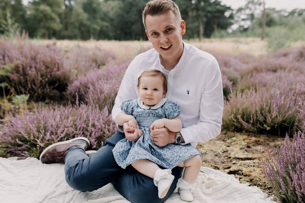 dad is holding his baby girl in his arms and looking at the camera smiling. creating family memories. family photo shoot outside in the nature common. Berkshire family photo shoot. Hampshire photographer. Ewa Jones photography