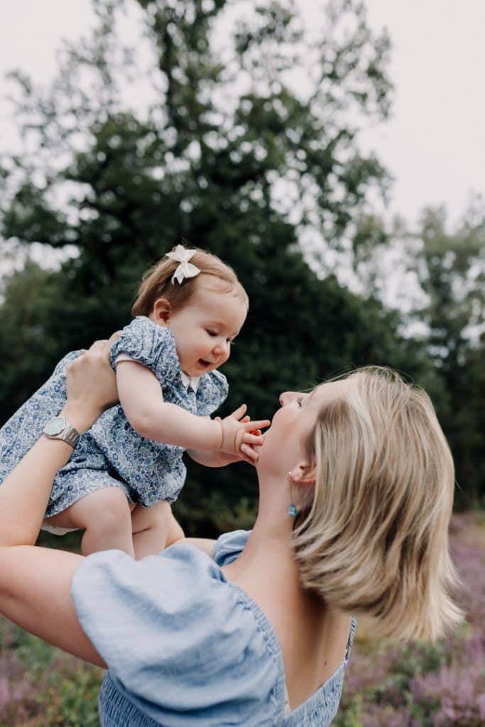 Mum is lifting up her girl and she is looking at her. girls wearing lovely blue dresses. what to wear for a family photo shoot. family photographer in Hampshire. Ewa Jones Photography