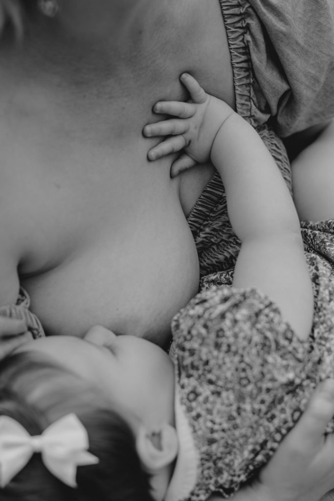 Close up detail of mother and baby. Baby girl is feeding and touching mums chest. Ewa Jones Photography