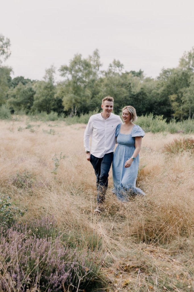 Couple is walking in the field and smiling. family photo session outside during summer time. Ewa jones Photography