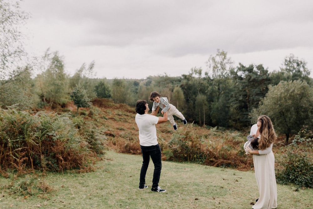 family is playing in the field and lifting their children. playful family photo shoot in Hampshire. Hampshire photographer. Ewa Jones Photography