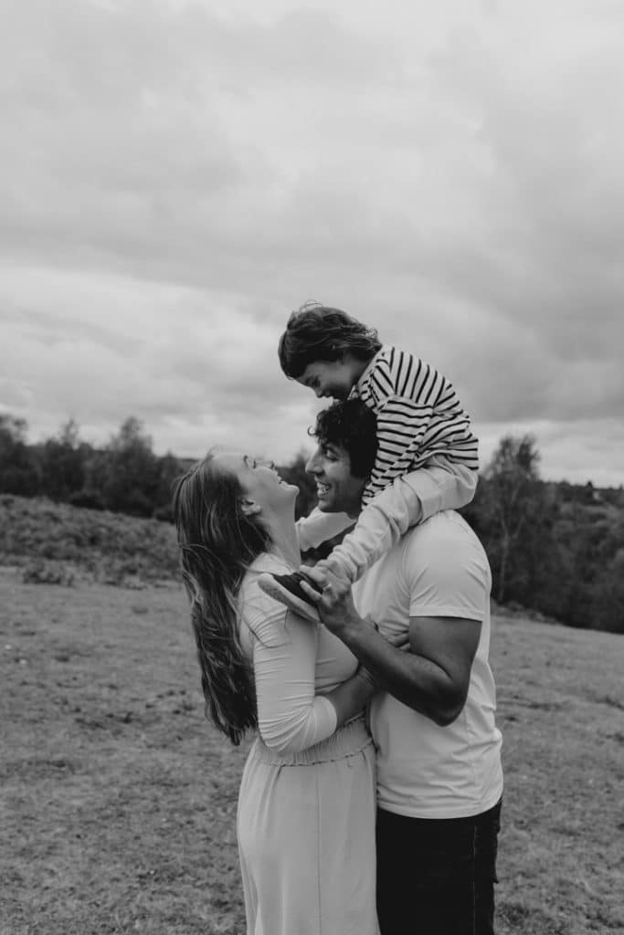 mum and dad are cuddling close and the son is smiling to mum. mum is smiling back. Hampshire family photo shoot. Ewa Jones Photography