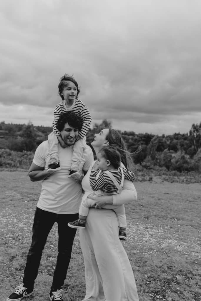 Black and white image of family standing in the field. Lovely family session, natural moments captured during family photo shoot. Ewa Jones Photography