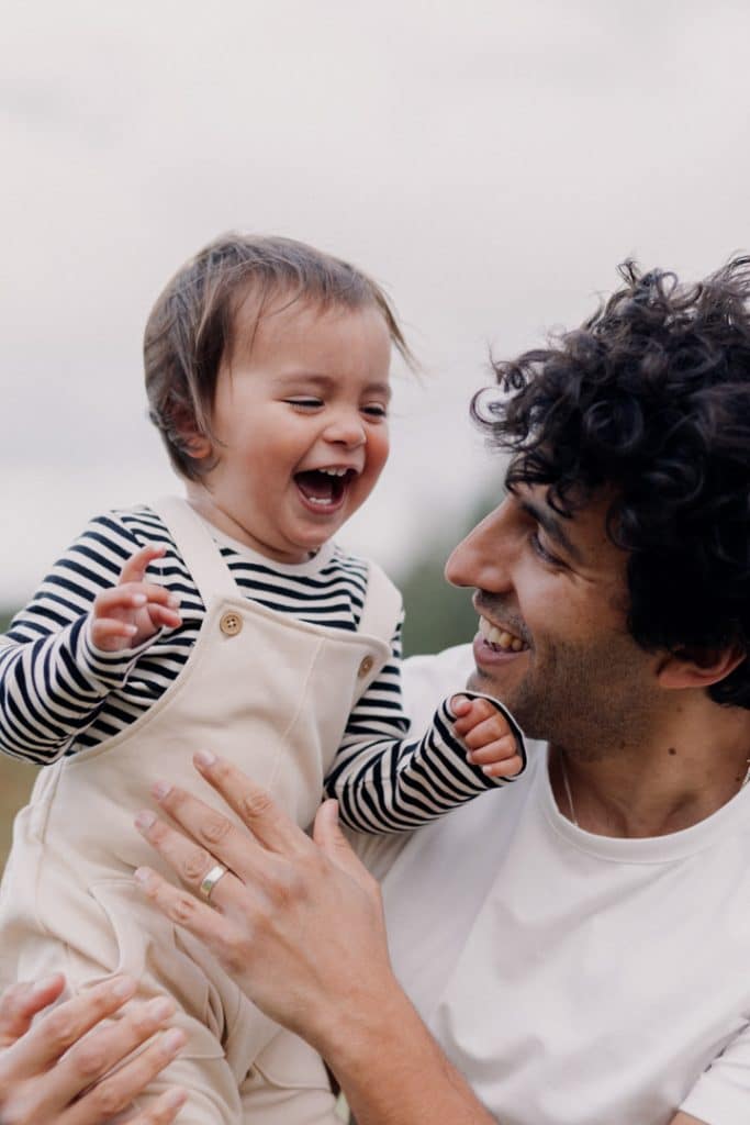 dad is holding his son in his arms and smiling at him. little boy is smiling too. Hampshire photo shoot. Hampshire photographer. Ewa Jones Photography