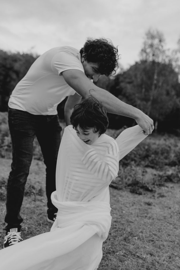 Dad is wrapping his son in the veil. fun family time during family session. Hampshire and Basingstoke family photographer. Ewa Jones Photography