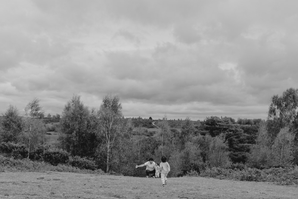 Dad is crouching down and waiting for his son to run up to him. natural family moment. lots of fun and smiles. Hampshire photographer. Basingstoke family photographer. Ewa Jones Photography