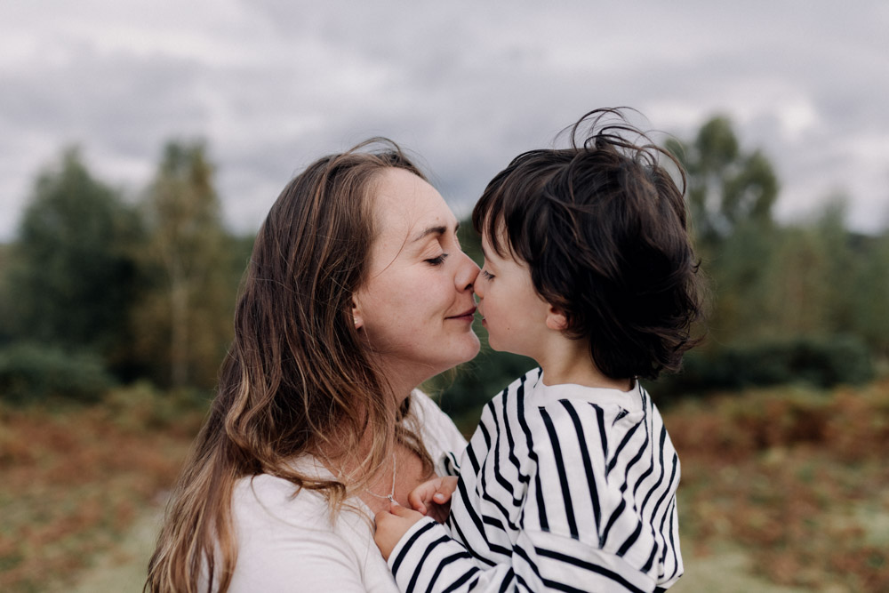 Mum and child are doing exkimo kisses. lovely playful pose during family photo session. Hampshire family photographer. Ewa Jones Photography