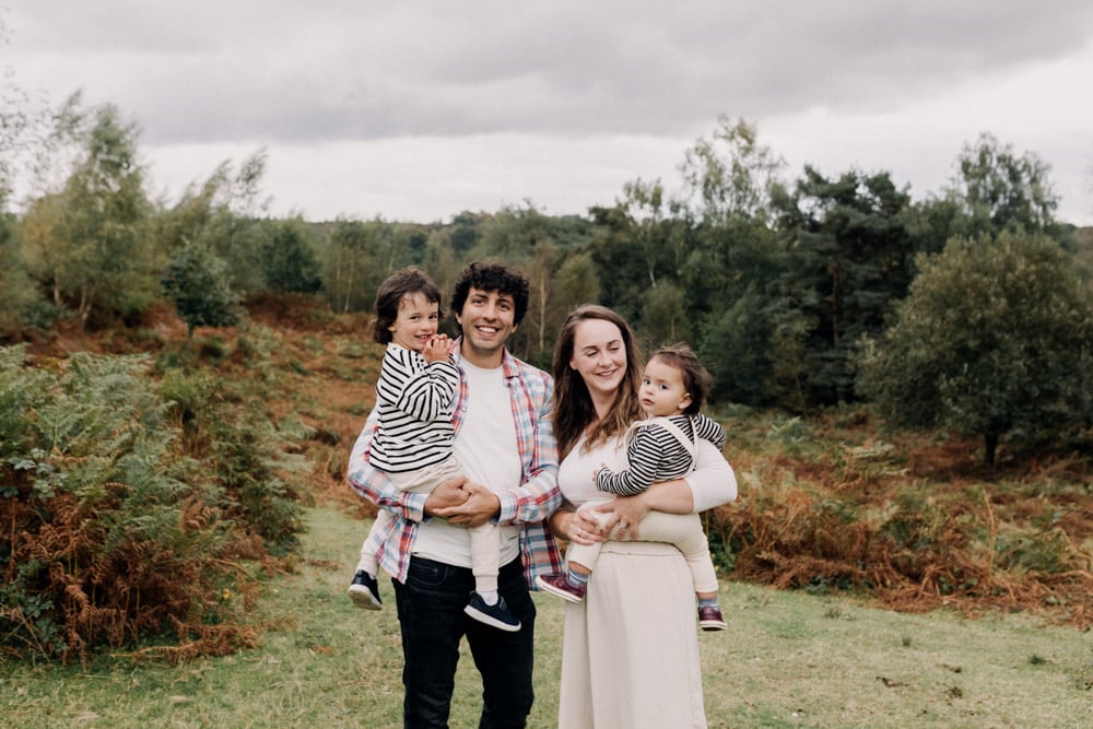 family is standing in the field and smiling to each other and camera. lovely New Forest setting. New Forest family photo shoot. Hampshire photographer. Ewa Jones Photography