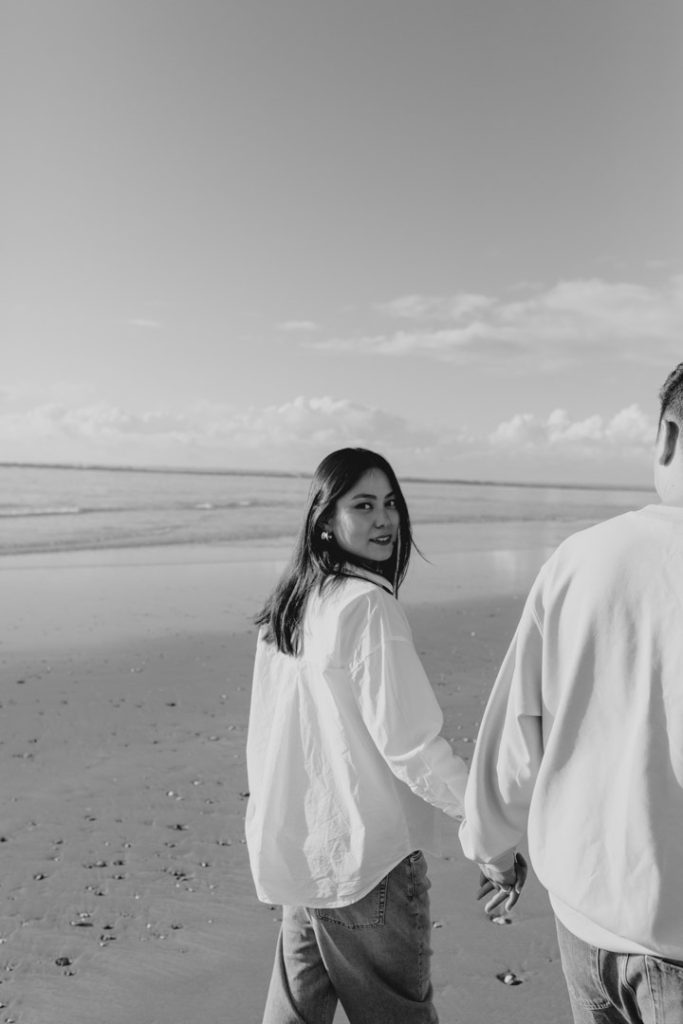Mum is walking away from the photographer and looking at the camera. image captured in a moment. maternity session at the beach. Hampshire family photographer. Ewa Jones Photography