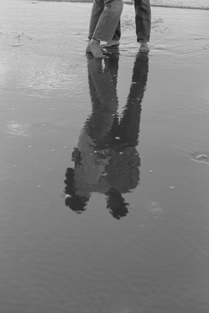 black and white reflection of the couple standing on the sand. great maternity photo shoot at the beach. Hampshire maternity photographer. bump photo session. Ewa Jones Photography
