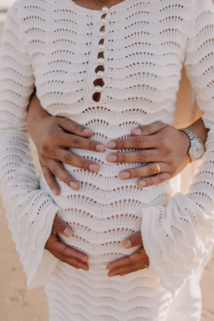 close up of both parents holding baby bump. mum is wearing white dress. Hampshire family photographer. Ewa Jones Photography