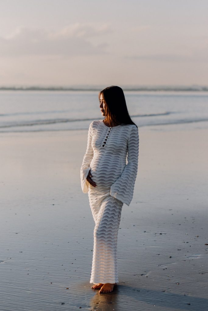 Mum is looking away at the sea. lovely sun is falling onto her dress. Maternity session. Hampshire photographer. Ewa Jones Photography