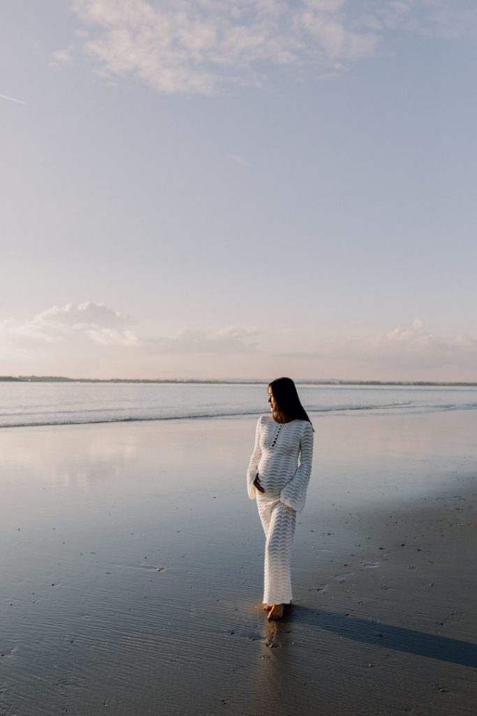 Mum is looking away at the sea. lovely sun is falling onto her dress. Maternity session. Hampshire photographer. Ewa Jones Photography