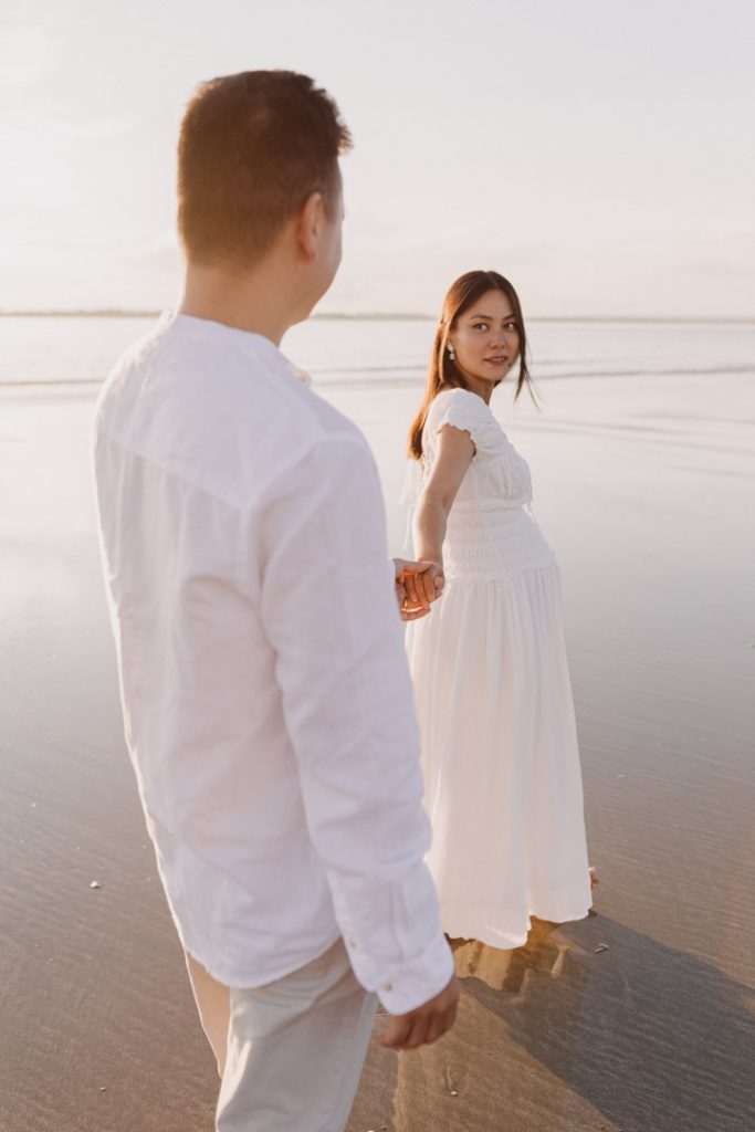 Mum is walking away from her husband and looking back at him, lovely natural photo session. parents are enjoying the session. bump and maternity photographer in Hampshire. Ewa Jones Photography