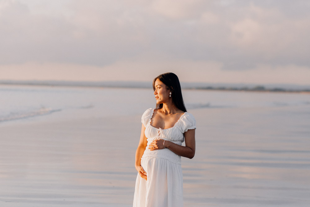 mum is looking into the sea and sun is shining on her. Maternity photo session. how to take maternity images at the beach. Hampshire photographer. Ewa Jones photography