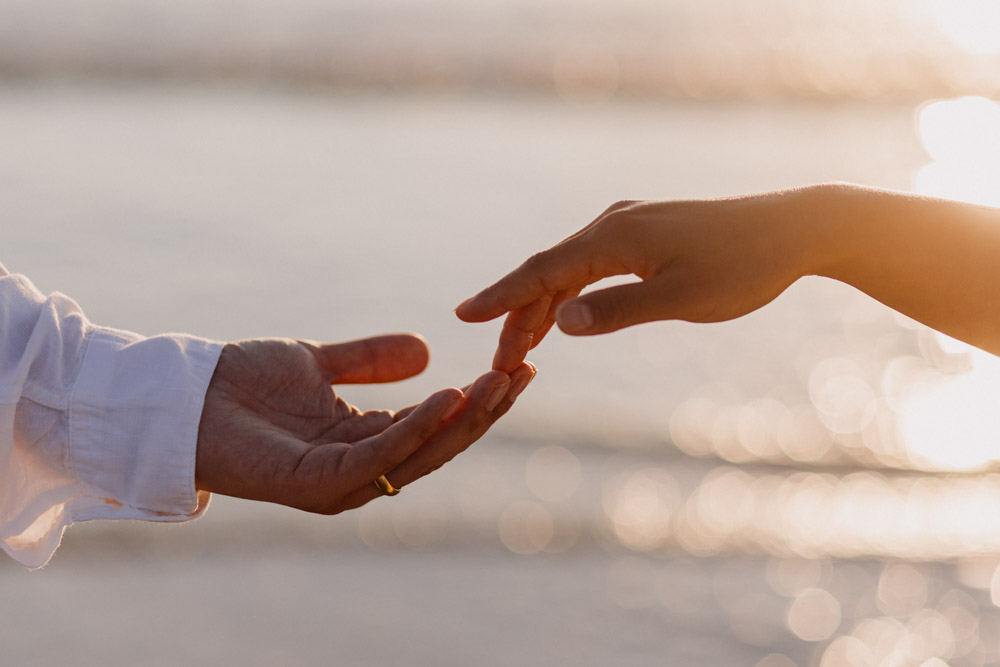 close up of hands. gentle natural photograph. sun is reflecting on sea water. Hampshire maternity photo session. Ewa Jones Photography