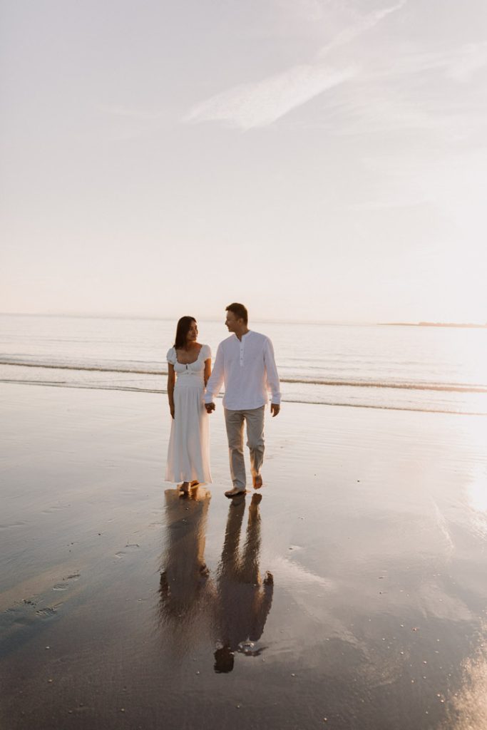 Parents to be are walking on the sand and smiling to each other. Maternity photo session at the beach. Ewa jones photography