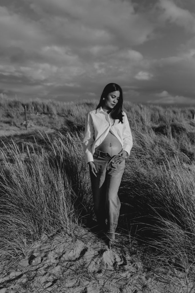 Mum to be is standing at the beach and looking down. Hampshire maternity photo shoot. natural maternity photography. Ewa Jones Photography