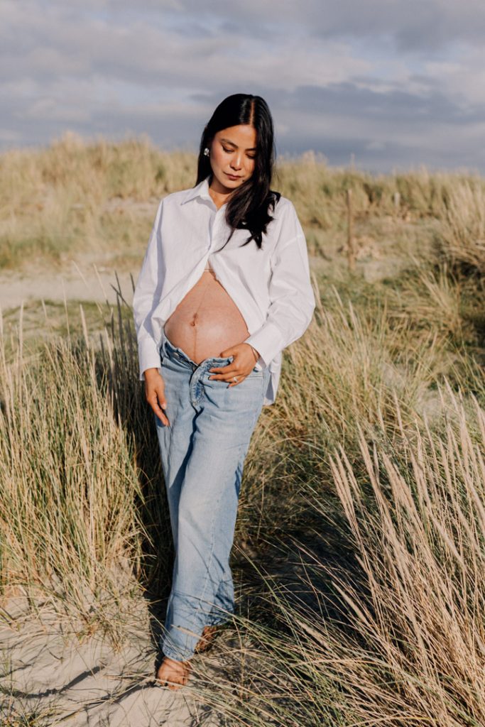 Mum to be is standing at the beach and looking down. Hampshire maternity photo shoot. natural maternity photography. Ewa Jones Photography