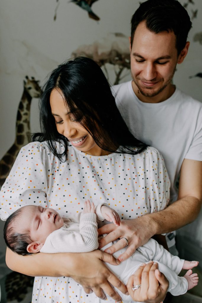 dad is cuddling mum and she is holding her newborn baby, lovely in home photo session. Natural photoshoot in your home. Hampshire and Basingstoke newborn photographer. Ewa Jones Photography