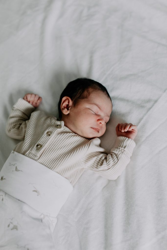 baby is sleeping and laying on the bed. Newborn photography in Hampshire. Ewa Jones Photography